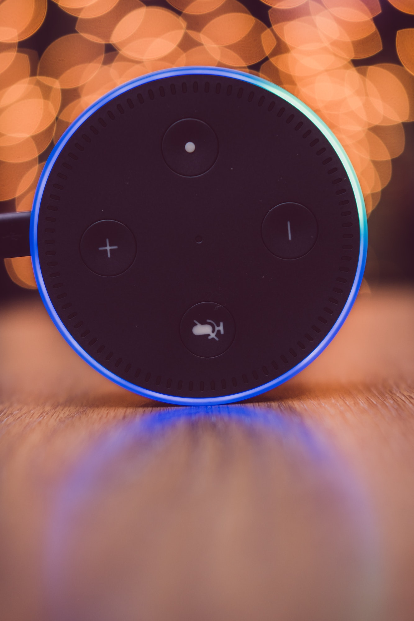 Amazon Alexa echo dot on wooden table with lights in the background, smart speaker, smart home